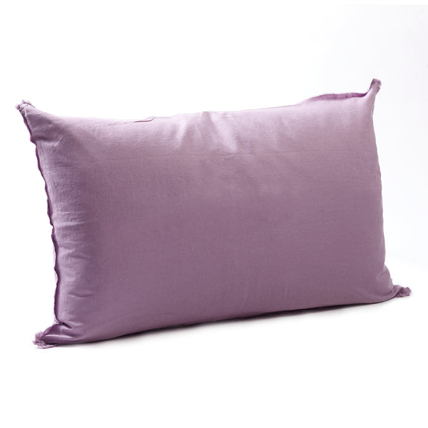 Soft jacaranda bedhead cushion in stonewashed French flax linen, with hand-tufted edges, offering a delicate, floral-inspired hue and sophisticated charm.