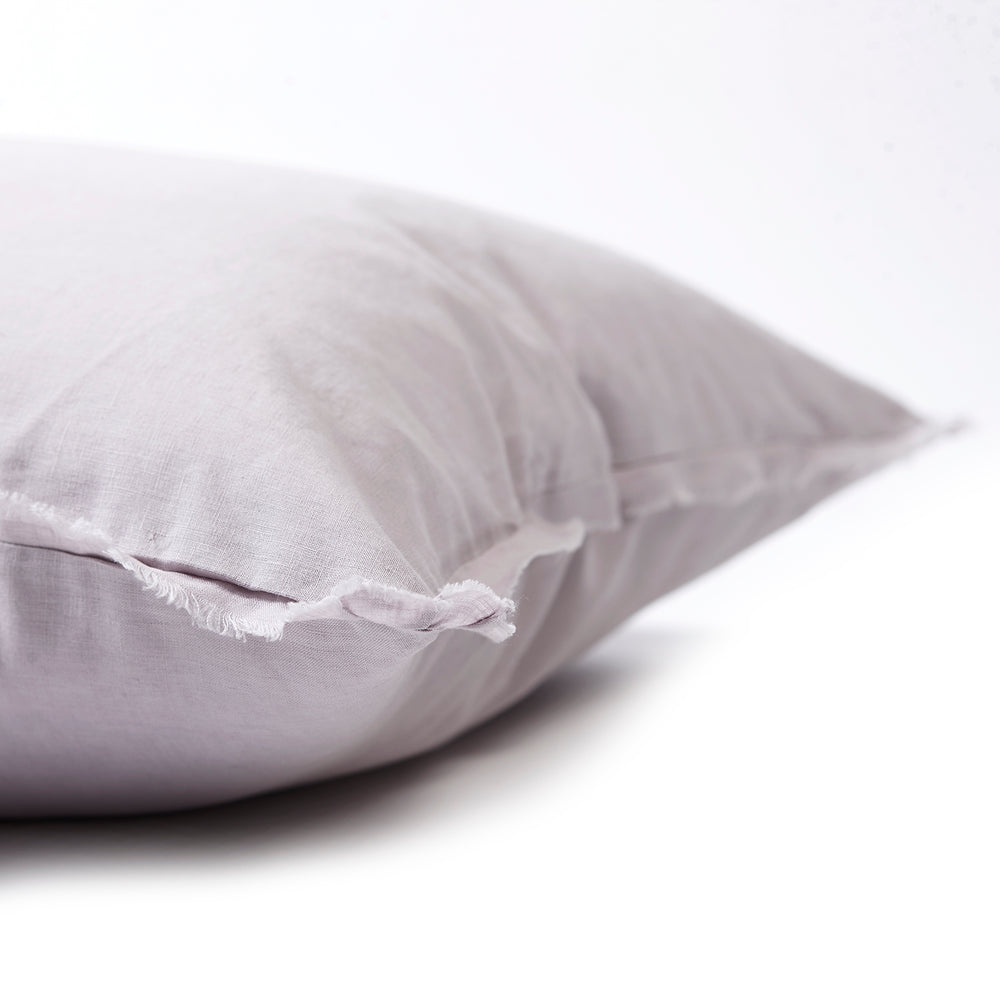 Soft lilac bedhead cushion in stonewashed French flax linen, with hand-tufted edges, offering a delicate, floral-inspired hue and a calming, elegant touch.